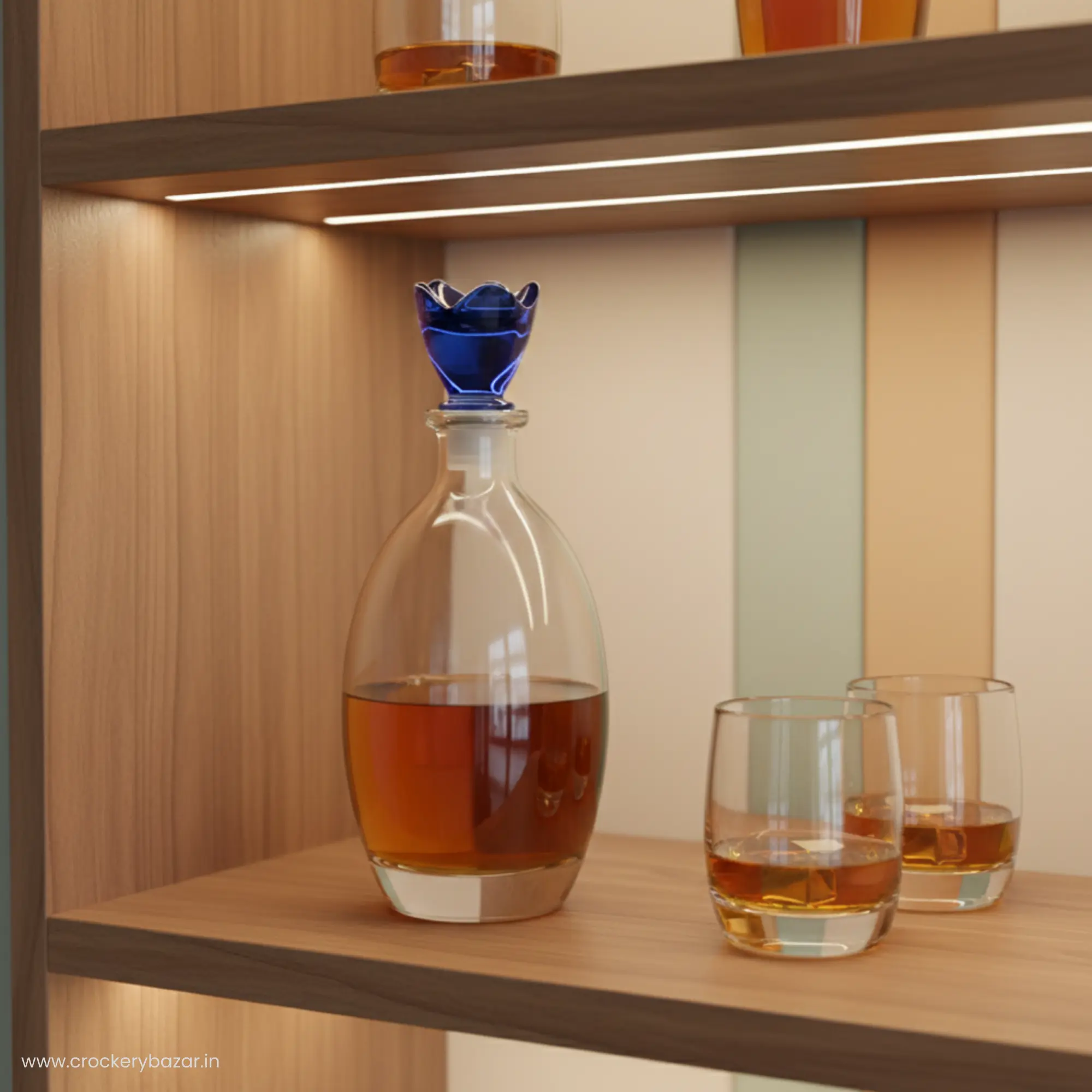 Bormioli Rocco Bouquet 780ml decanter with blue flower lid displayed on a wooden bar shelf next to matching whiskey glasses.