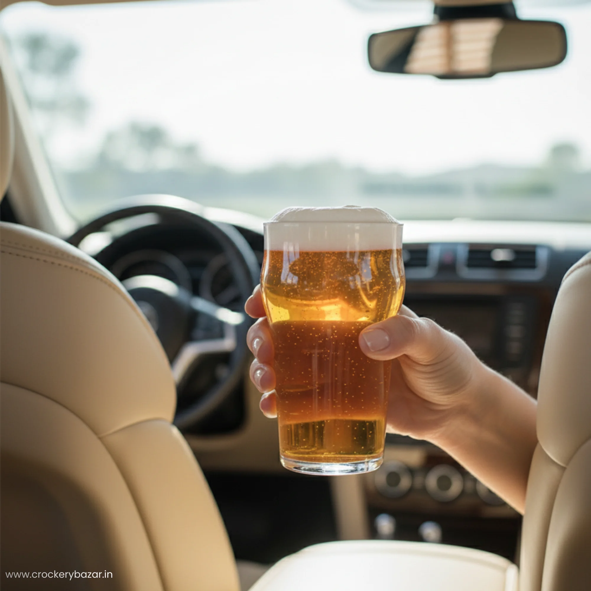 A hand holding a Stout beer glass filled with lager and foam inside a car, showing the ergonomic grip of the Nonic shape beer glass large .