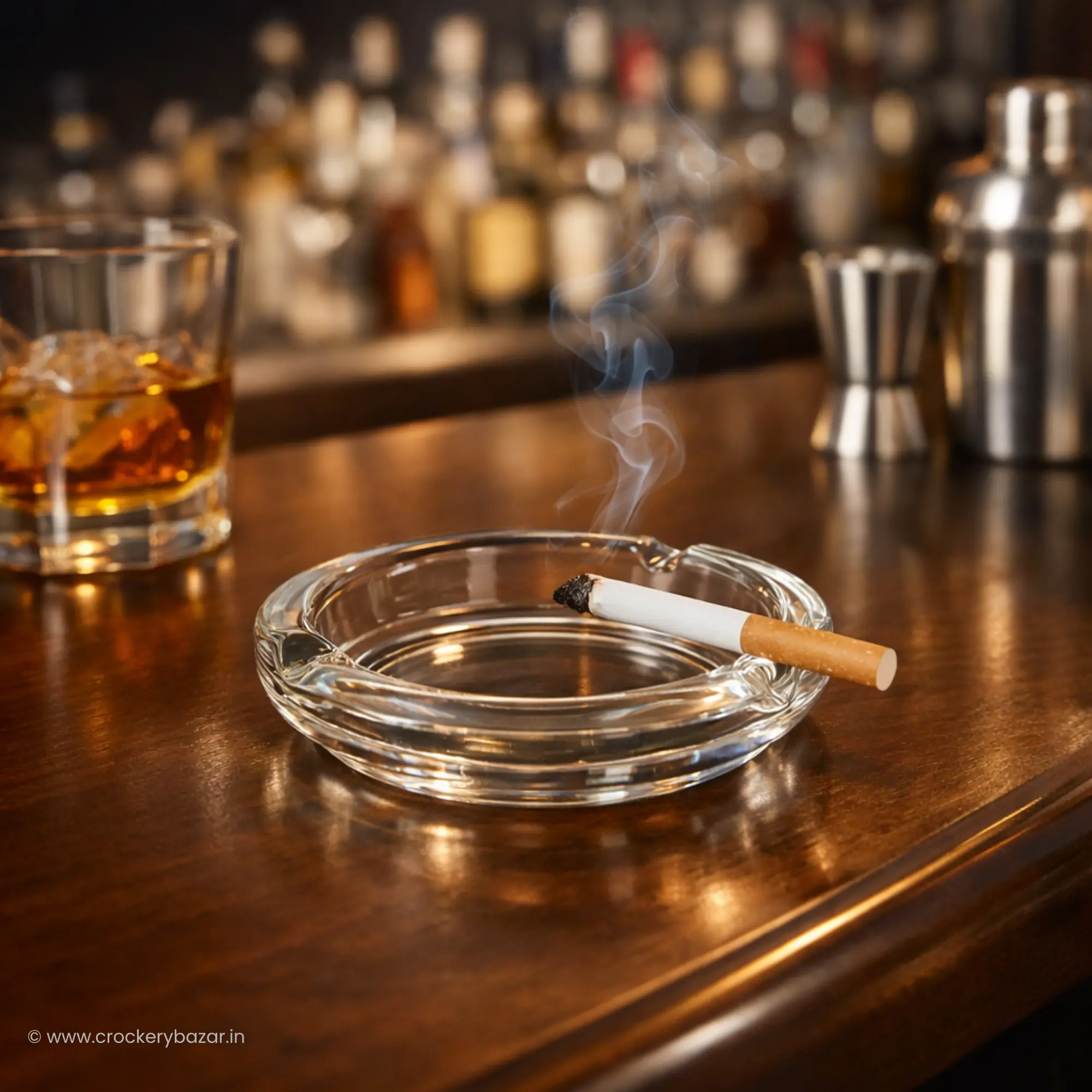 Bormioli Rocco Poker small glass ashtray for smoking on a dark wood bar counter with a whiskey glass.