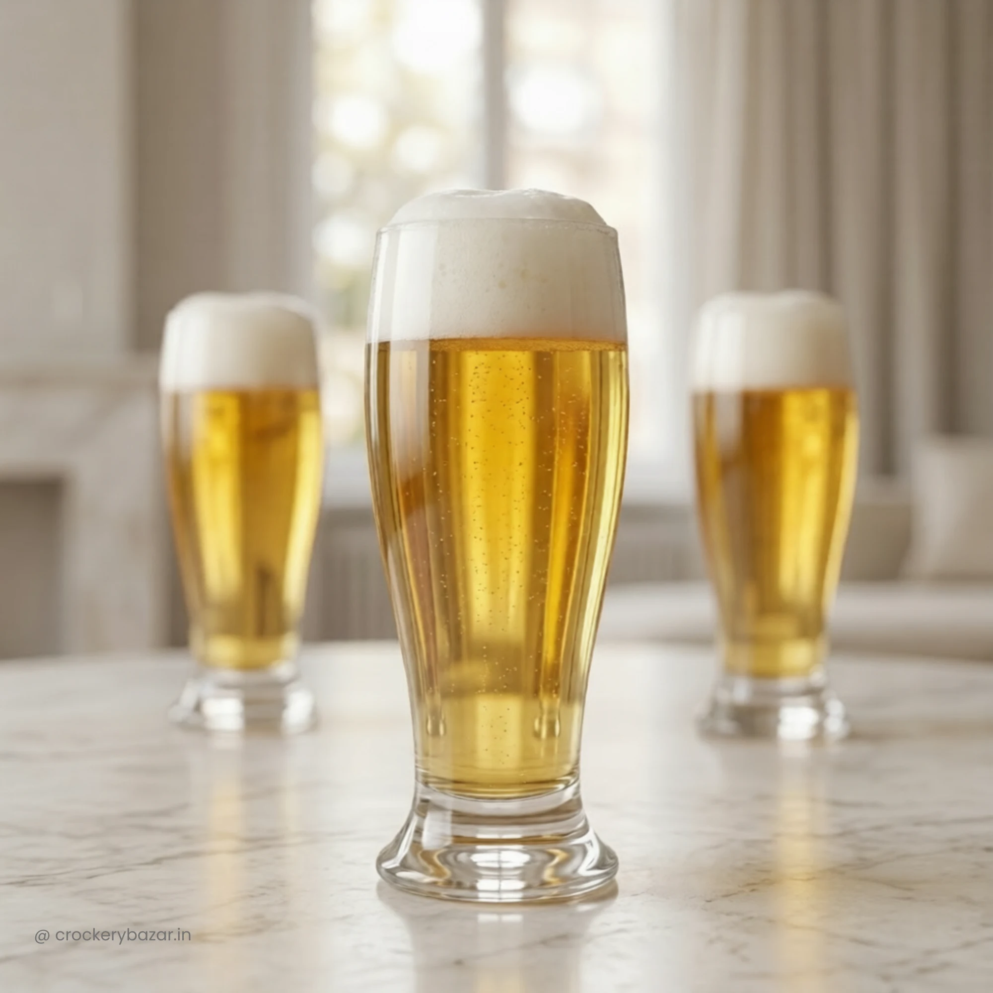 Three Nadir Munich 200ml pilsner beer glasses with clear carbonation and thick foam heads arranged on a white marble table in a bright living room.