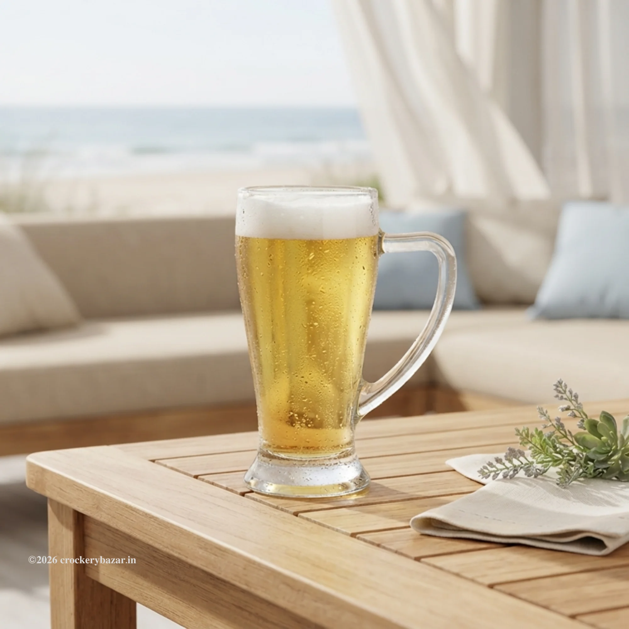 Bormioli Rocco Baveria unique glass beer mug 400 ml with handle filled with iced golden beer on an outdoor wooden patio table near the beach.